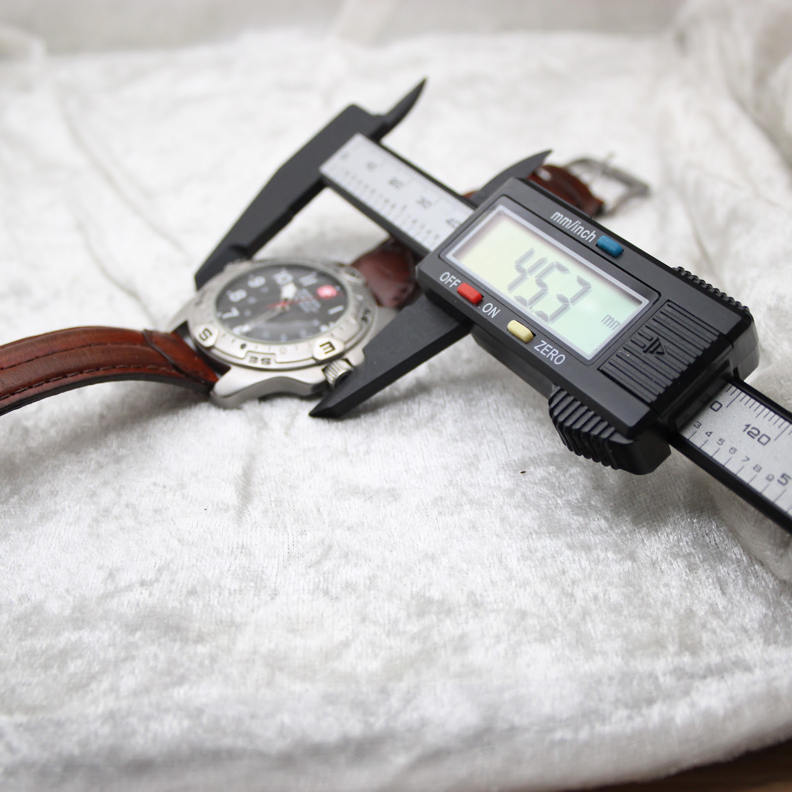 Digital caliper measuring the watch case, displaying a precise diameter of 45.3mm.