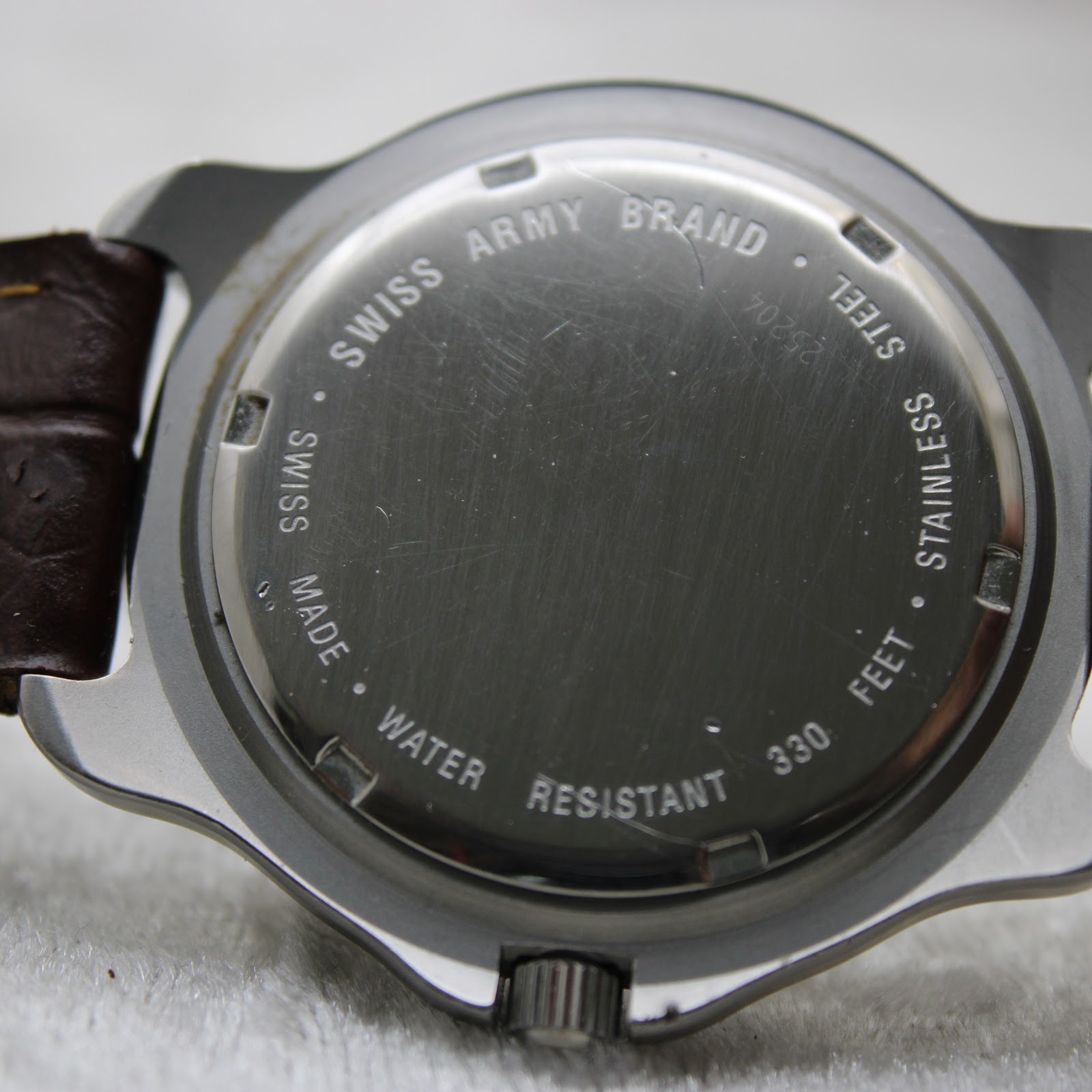 Close-up of the stainless steel caseback showing "SWISS ARMY BRAND", "WATER RESISTANT 330 FEET", and "SWISS MADE" engravings.