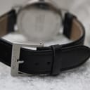 Close-up shot of the black leather strap with a brushed stainless steel buckle, clearly showing the "MONDAINE" signature engraved on it.