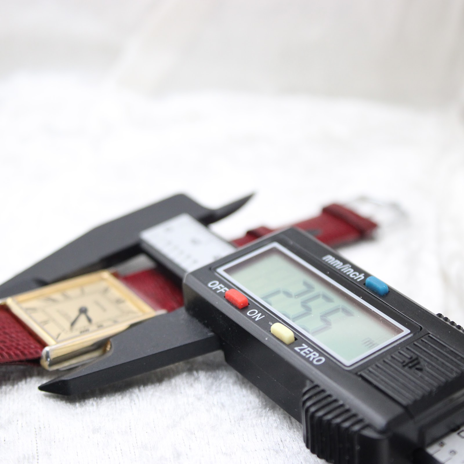 Digital caliper measuring the width of the Corteal watch case at 25.5mm, with the watch resting on a white surface.