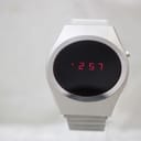 Front view of the unbranded vintage LED digital watch with the red display showing '2:57'. The case is brushed silver-tone.