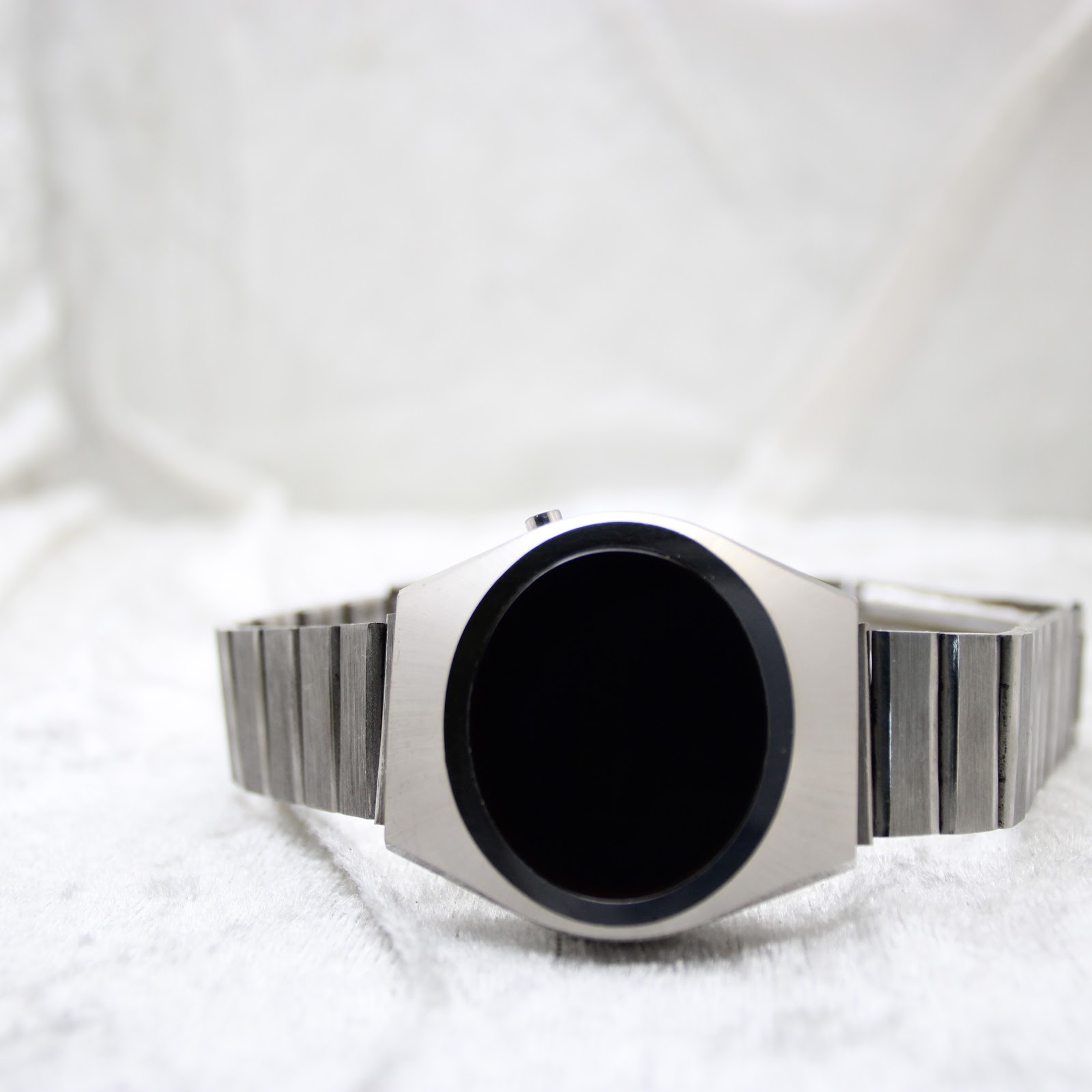 Front view of the unbranded LED digital watch with the display off, showing the dark, blank face and brushed silver case.