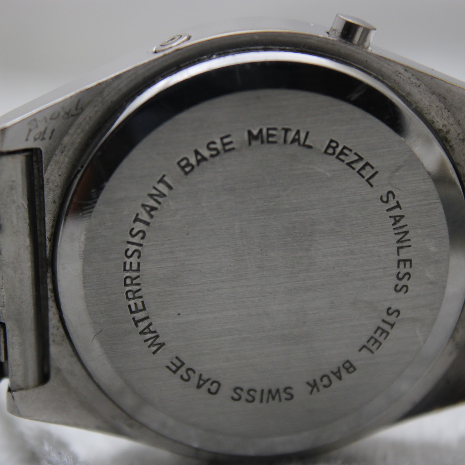 Close-up of the stainless steel case back, clearly showing "waterresistant base metal bezel stainless steel back swiss" engraving.