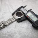 Overhead view of the unbranded LED digital watch on a white surface, with a digital caliper measuring the case diameter at 35.6mm.