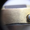 Close-up side view of the watch case, showing the 'PLAQUE G10' engraving which signifies gold plating, alongside the brushed finish.