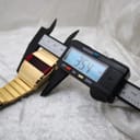 Digital caliper measuring the width of the watch case, displaying a precise measurement of 35.4mm on its screen.