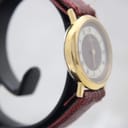 Angled side view of the gold-tone Burberrys watch case and burgundy leather strap.