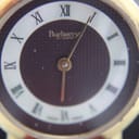 Close-up of the Burberrys of London dial, showing the textured burgundy centre and white Roman numeral chapter ring.