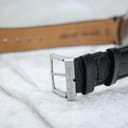 Close-up of the silver-toned buckle on the black leather strap, signed 'Eco-Drive'.