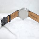 View of the watch from the back, showing the case back and the interior of the black leather strap with "genuine leather" and "20" markings.