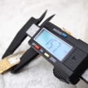 Digital caliper measuring the case diameter of the Bulova watch, displaying an exact measurement of 15.7mm.