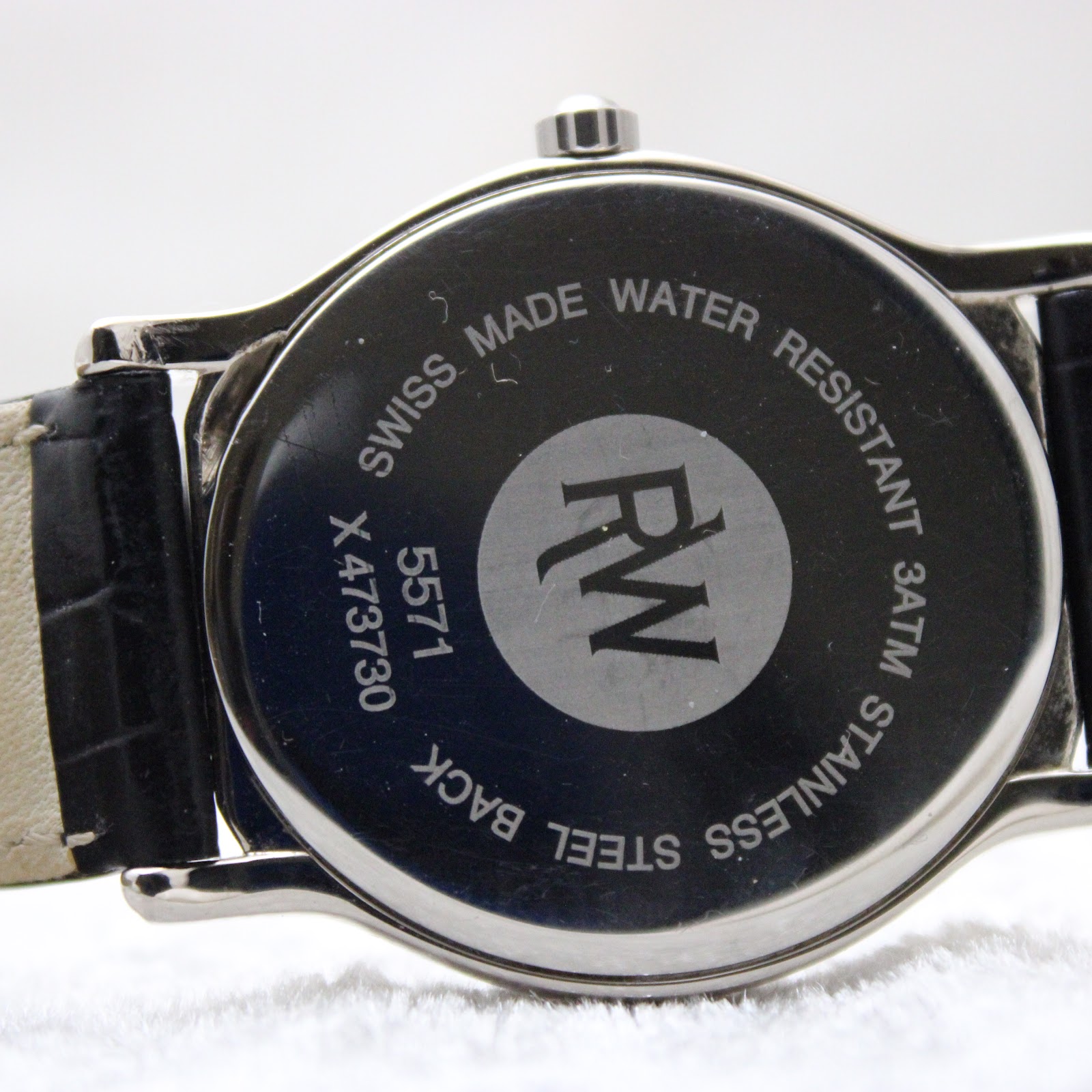 Close-up of the polished stainless steel case back with "Swiss Made Water Resistant 3ATM Stainless Steel Back" and serial number X473730.