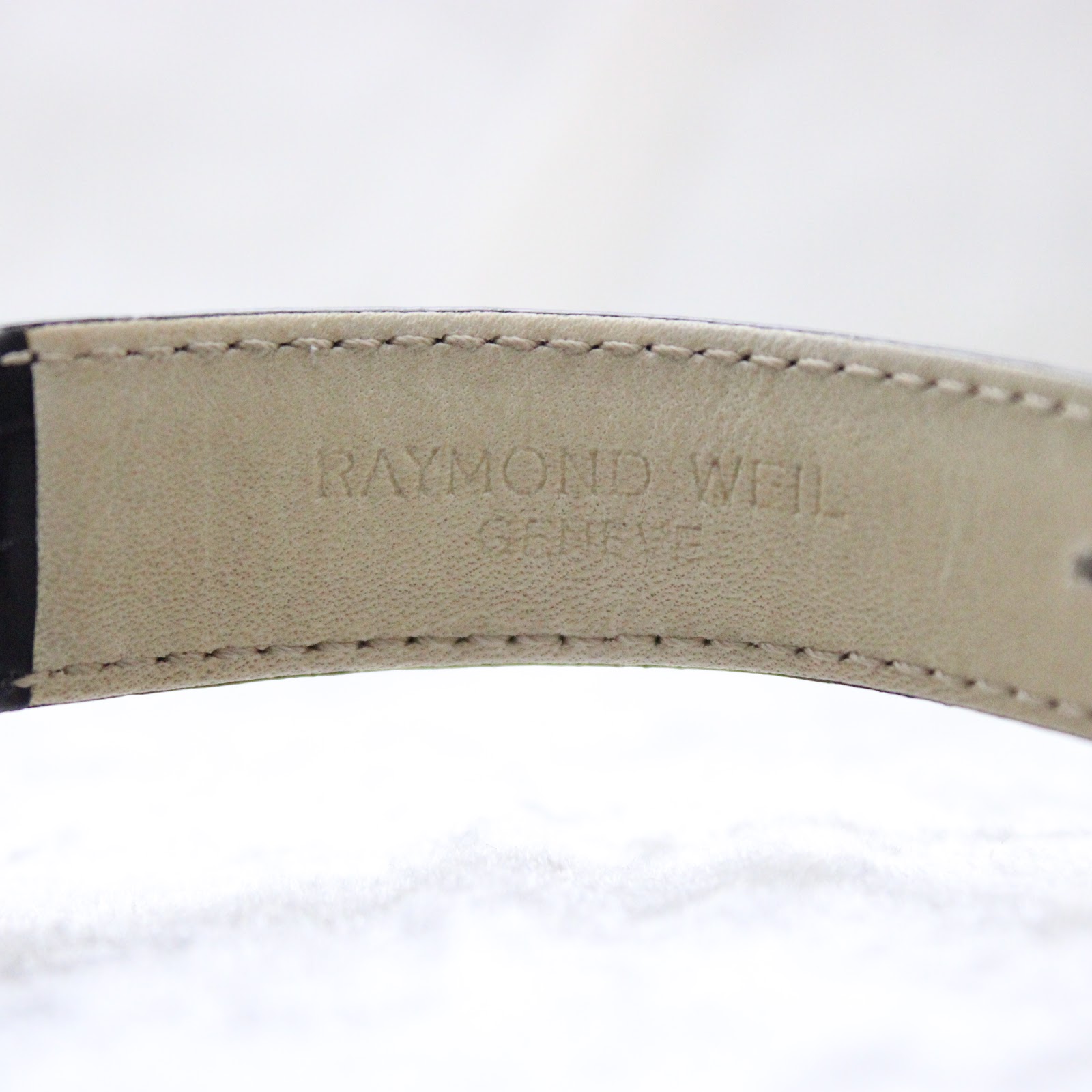 Interior view of the black leather strap showing "Raymond Weil Genève" embossed.
