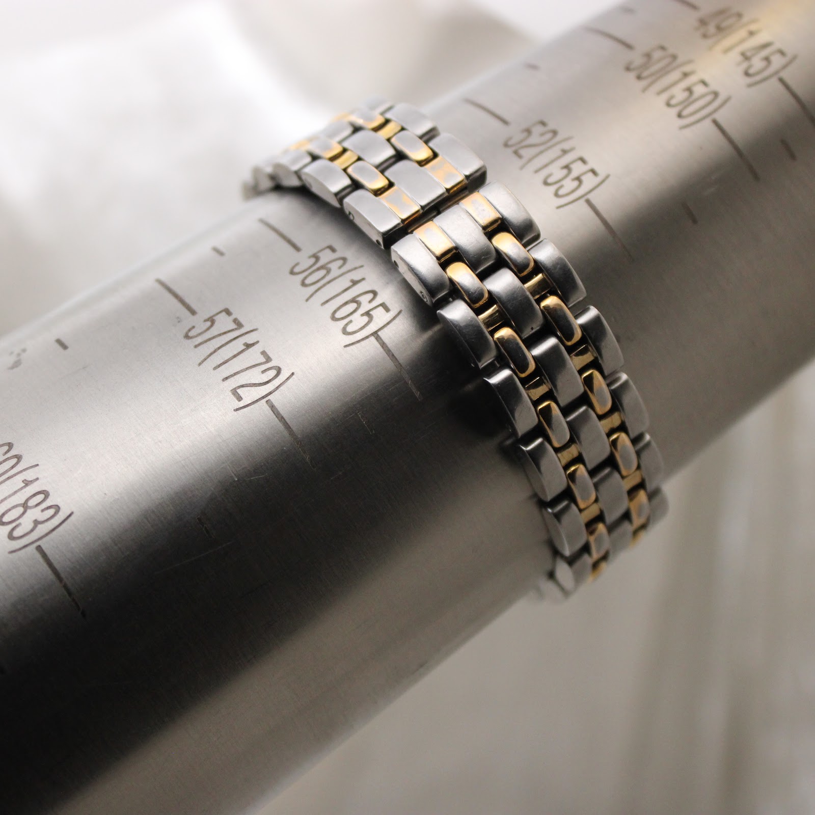 The bi-tone bracelet on a wrist sizing gauge, showing a circumference of 165mm.