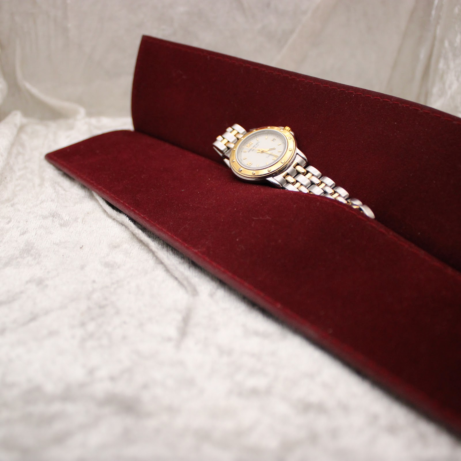 Elevated view of the Raymond Weil Tango watch inside the red velvet presentation pouch.