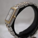 Right side profile view of the Raymond Weil Tango watch on a display stand, showing the gold-tone fluted crown and case side.