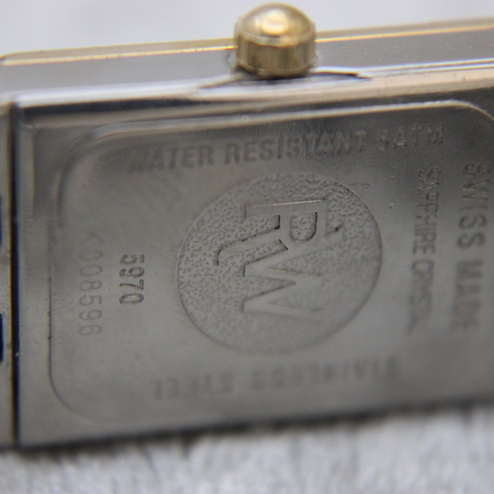 Close-up of the stainless steel case back of the Raymond Weil Tango, showing 'Water Resistant 5ATM', 'Swiss Made', 'Sapphire Crystal', 'RW' logo, model '5970', and serial 'K008596'.