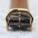 Macro shot of the gold-tone buckle, clearly displaying the iconic 'RW' Raymond Weil logo.