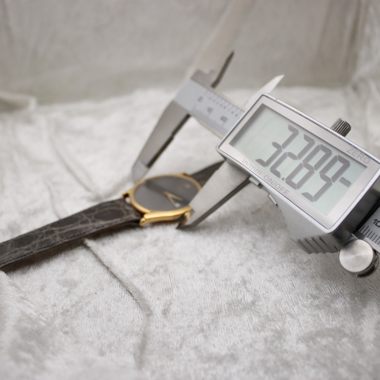Digital caliper measuring the watch case diameter at 32.89mm, with the watch visible in the background.