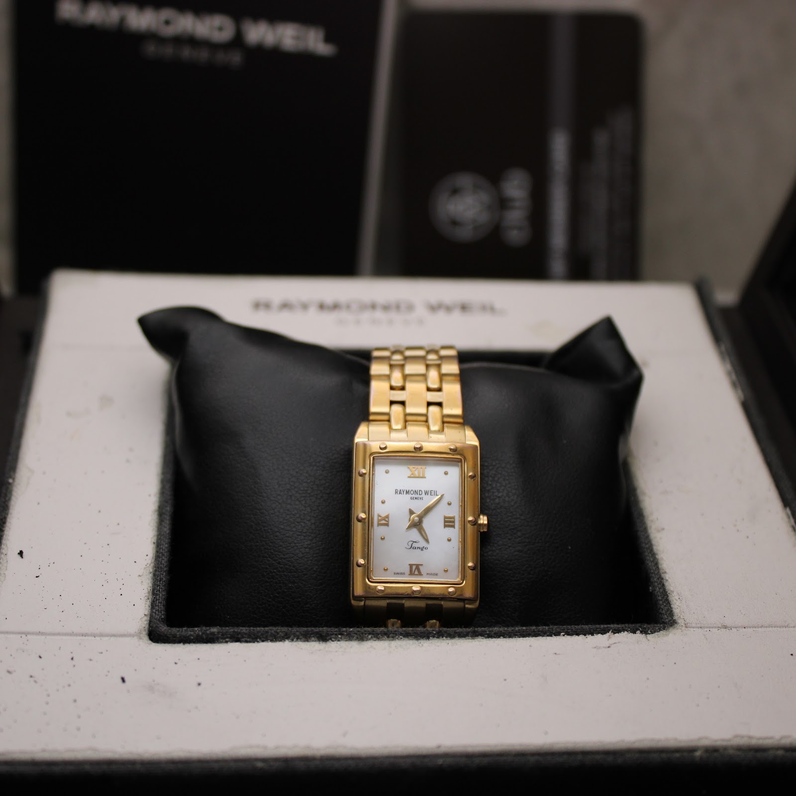 Front view of the watch resting on a cushion inside its original Raymond Weil presentation box