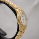 Another side view of the watch case, highlighting the smooth lines and gold finish of the case and lugs.