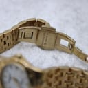 Close-up of the watch's gold-tone deployment clasp, clearly showing the 'Raymond Weil Geneve' signature engraving.