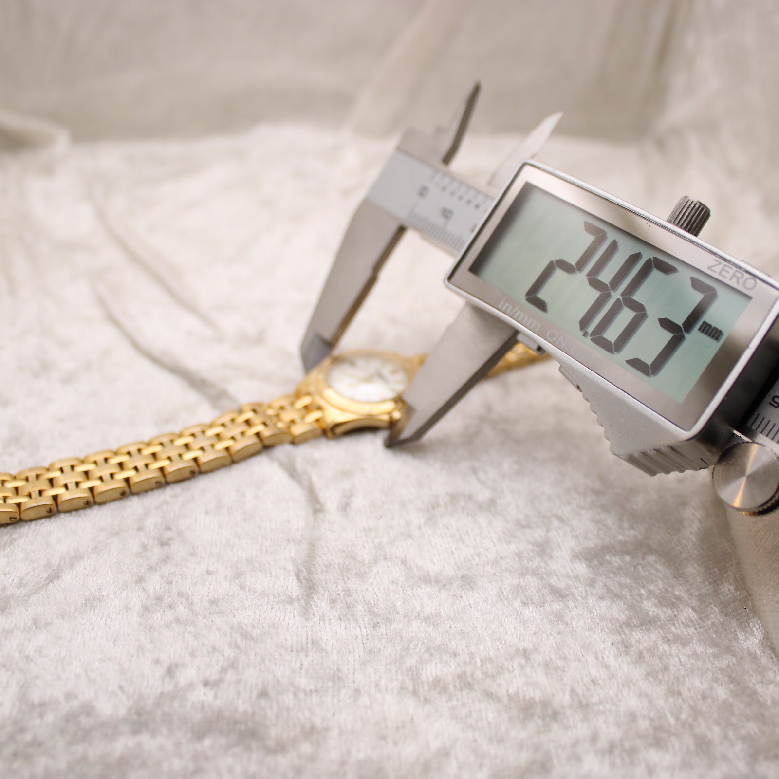 Digital caliper measuring the watch case, displaying a precise diameter of 24.63mm.