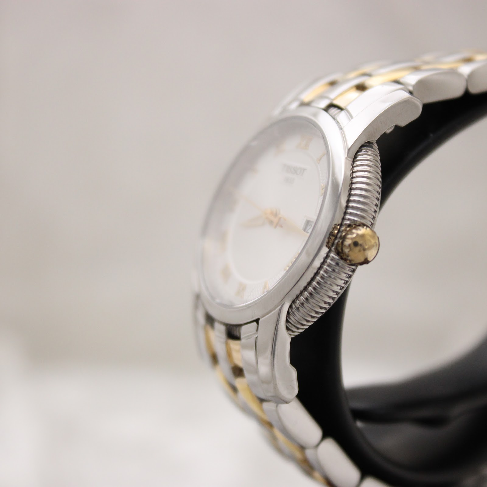 Angled side view of the watch, showing the fluted gold-tone bezel and gold-tone crown details.