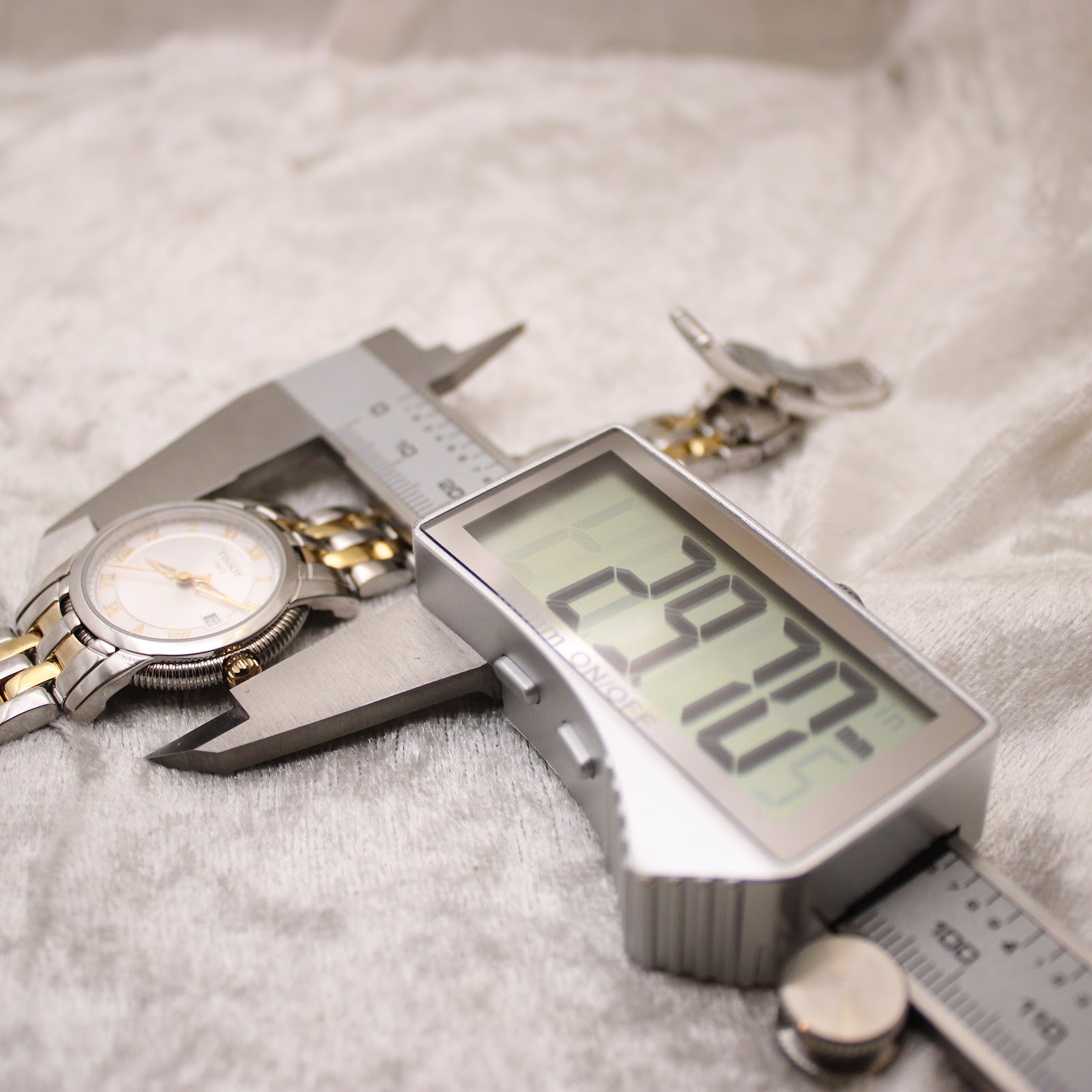 Digital caliper measuring the watch case diameter, showing a precise reading of 28.70 mm.
