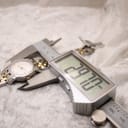 Digital caliper measuring the watch case diameter, showing a precise reading of 28.70 mm.