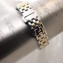 The watch bracelet on a wrist sizing gauge, showing 'TISSOT 1853' on the clasp and indicating a wrist size of approximately 155mm.