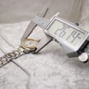 Digital caliper measuring the watch case diameter, displaying 26.14mm.