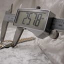 Digital caliper measuring the watch case diameter, showing a precise reading of 25.78mm.
