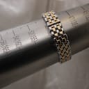 Close-up of the two-tone bracelet on a wrist sizing gauge, indicating a wrist circumference of approximately 15cm (150mm).