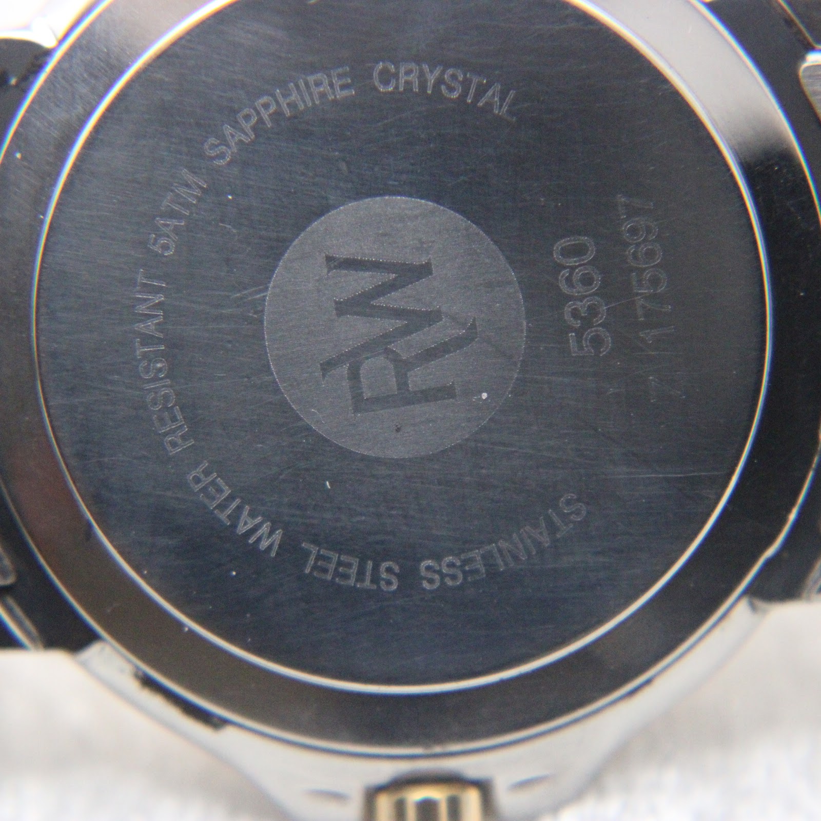 Close-up of the watch case back, engraved with 'stainless steel', 'water resistant 5atm', 'sapphire crystal', and model number 5360.