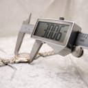 Digital caliper measuring the watch case, displaying a diameter of 30.06mm, on a light-coloured textured surface.