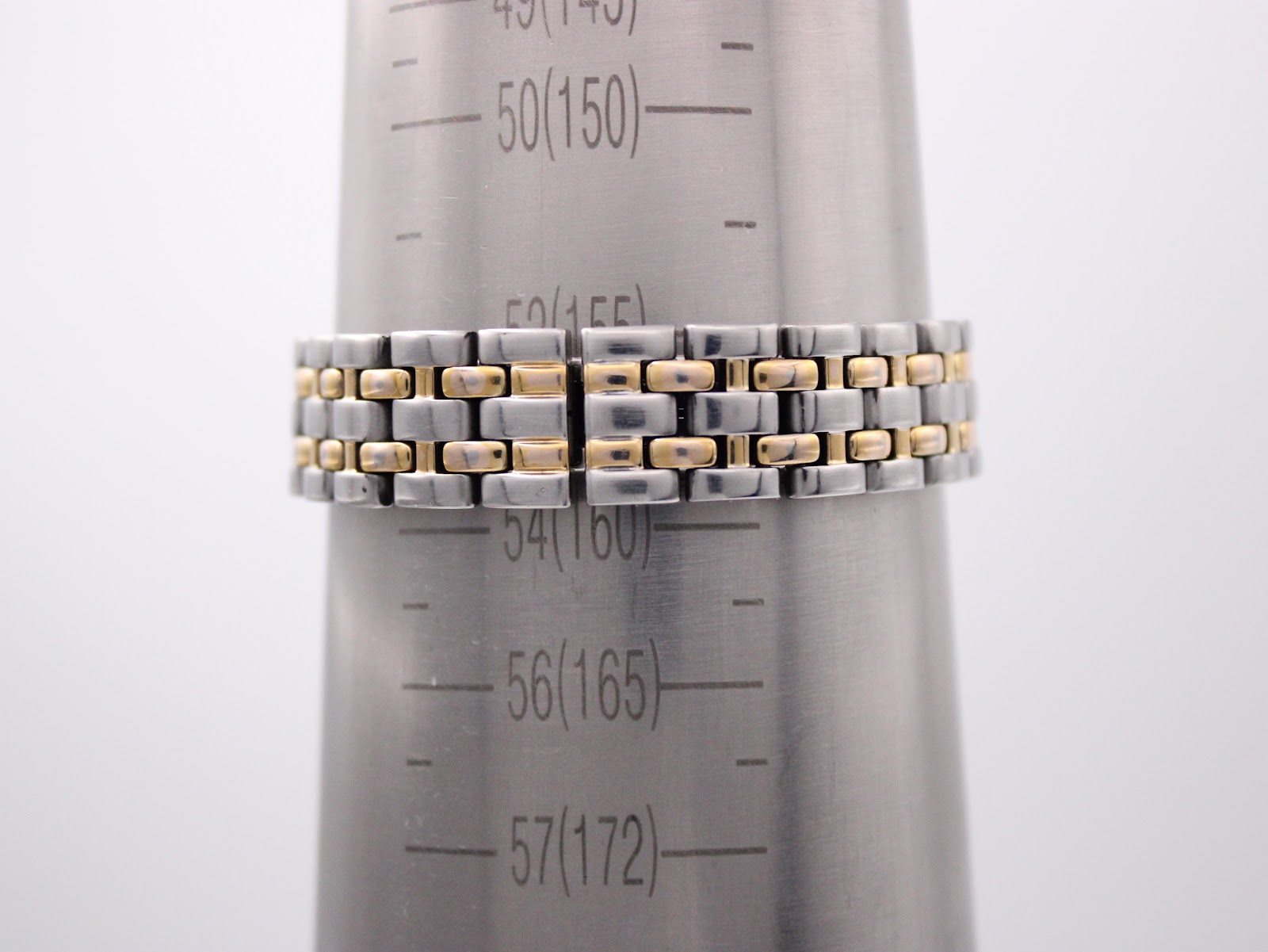 Close-up of the two-tone stainless steel bracelet on a wrist sizing gauge, showing a measurement of 57mm / 17.2cm.