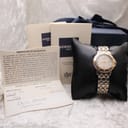 Raymond Weil watch displayed on a cushion, surrounded by its original certificate of guarantee, instruction booklet, and outer box.