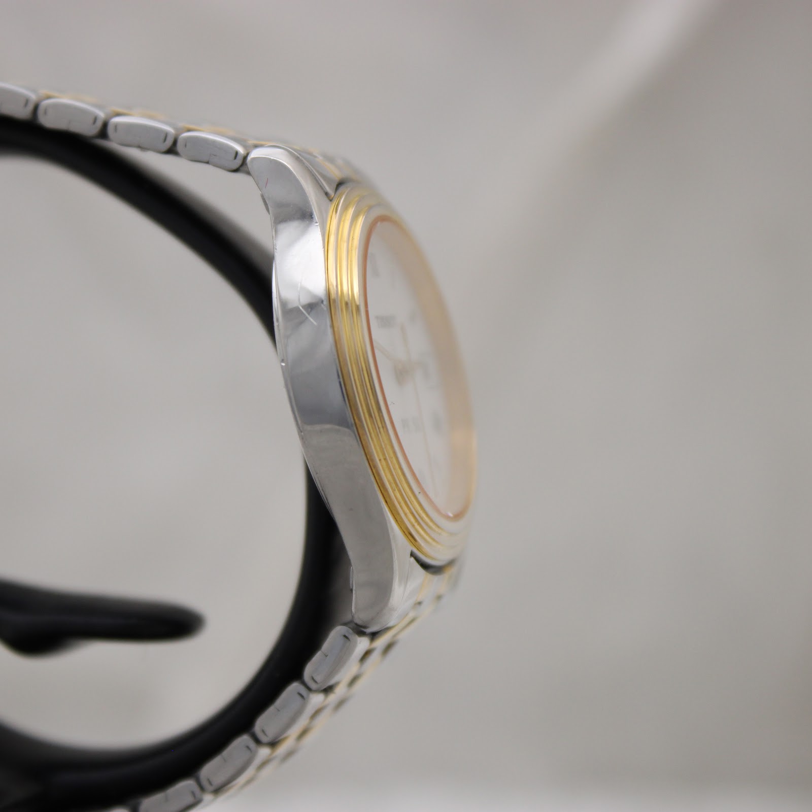 Another side profile of the Tissot PR 50 watch, highlighting the two-tone bracelet links and the curved lugs of the stainless steel case.