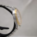 Another side profile of the Tissot PR 50 watch, highlighting the two-tone bracelet links and the curved lugs of the stainless steel case.
