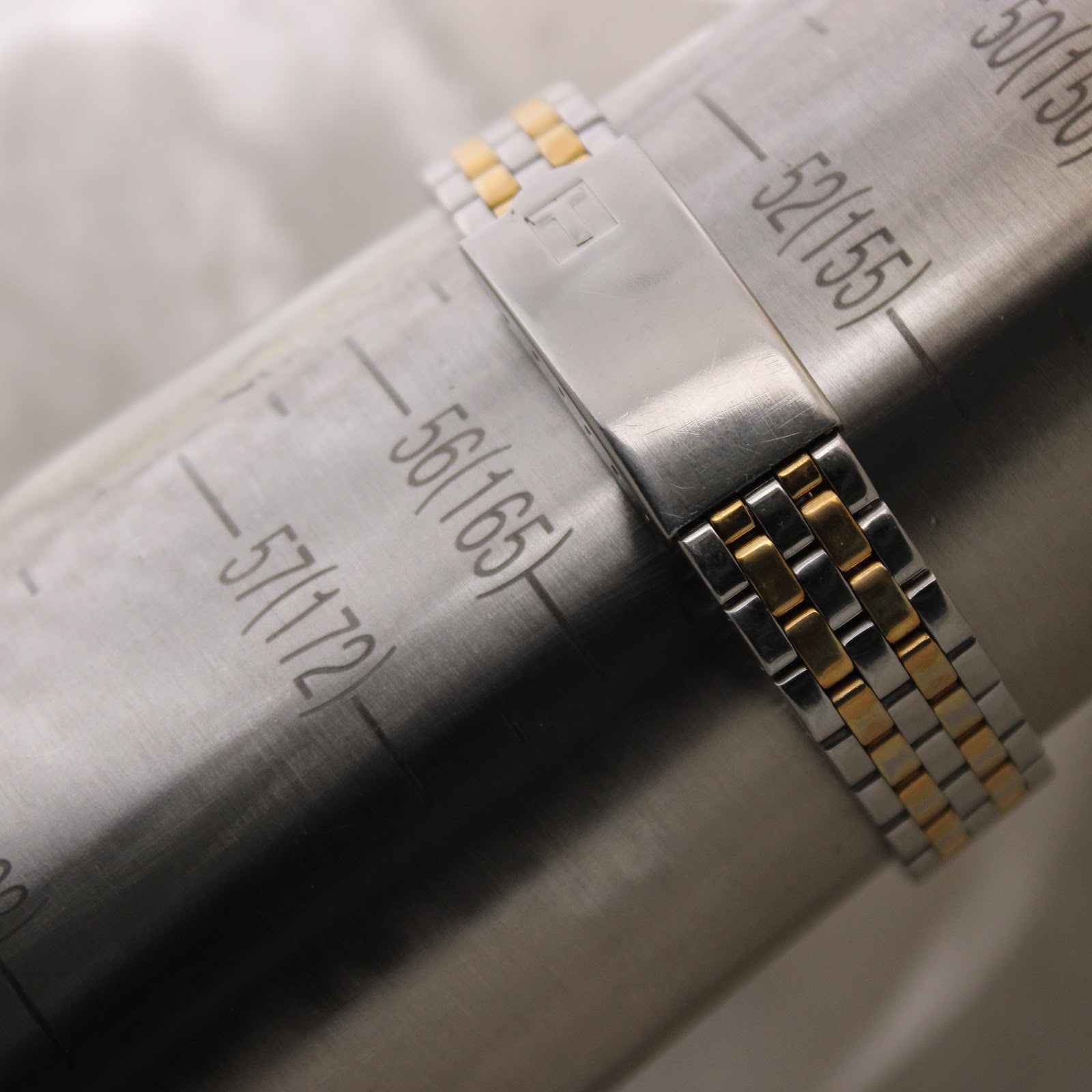 The two-tone stainless steel bracelet of the Tissot PR 50 watch displayed on a metallic wrist sizing gauge, indicating a size of approximately 160mm.