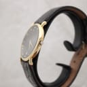 Right-side view of the gold-plated Raymond Weil 9124 case and original gold-tone crown, showing the watch on its black leather strap.