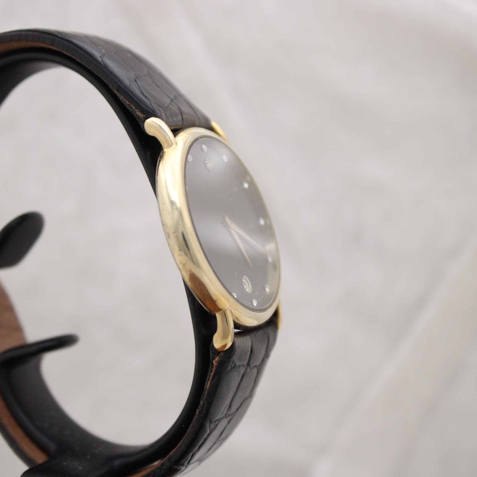 Left-side view of the sleek gold-plated Raymond Weil 9124 case, highlighting its slim profile and the black leather strap.