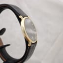 Left-side view of the sleek gold-plated Raymond Weil 9124 case, highlighting its slim profile and the black leather strap.