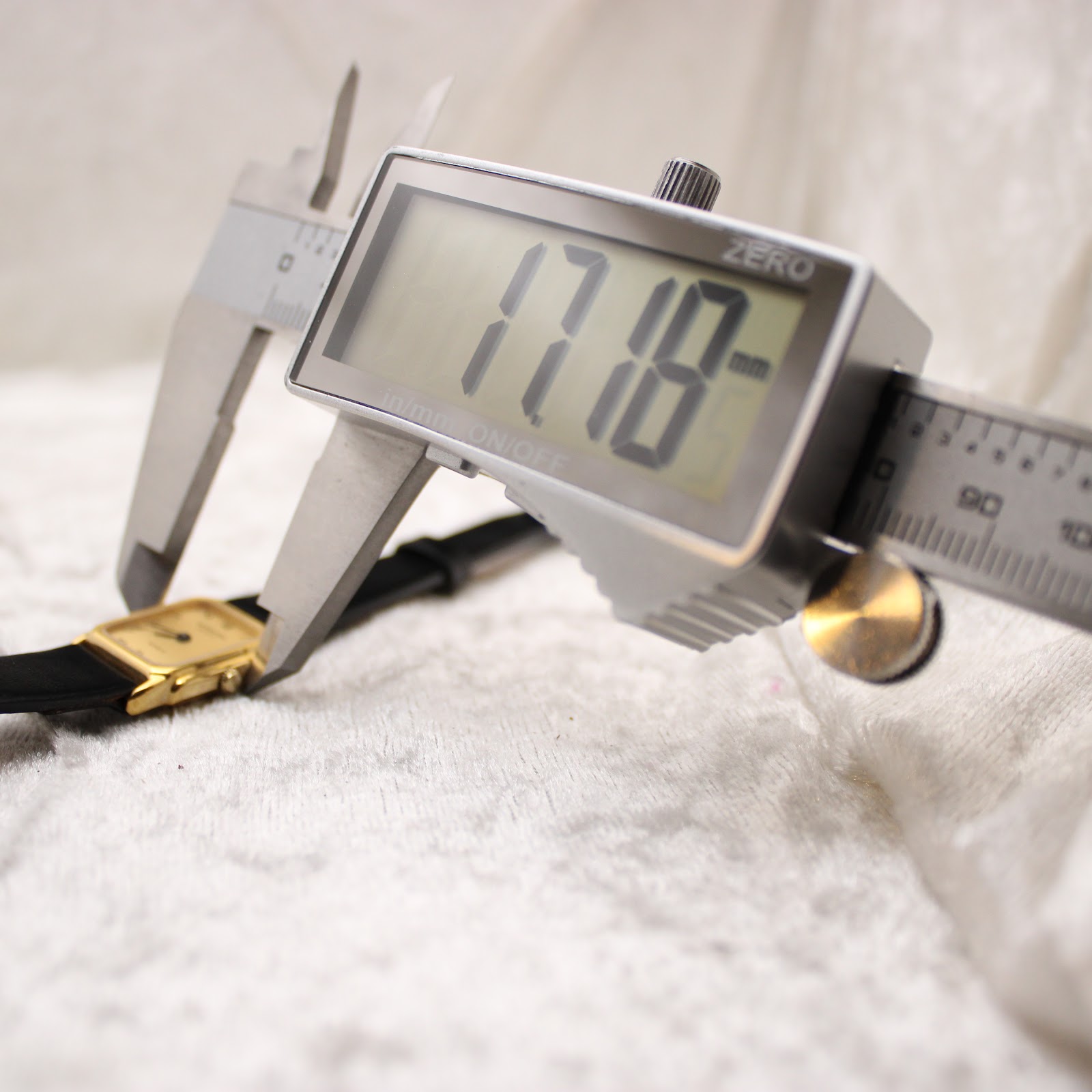Digital caliper measuring the watch case, displaying a precise measurement of 17.18mm, confirming the exact case size.