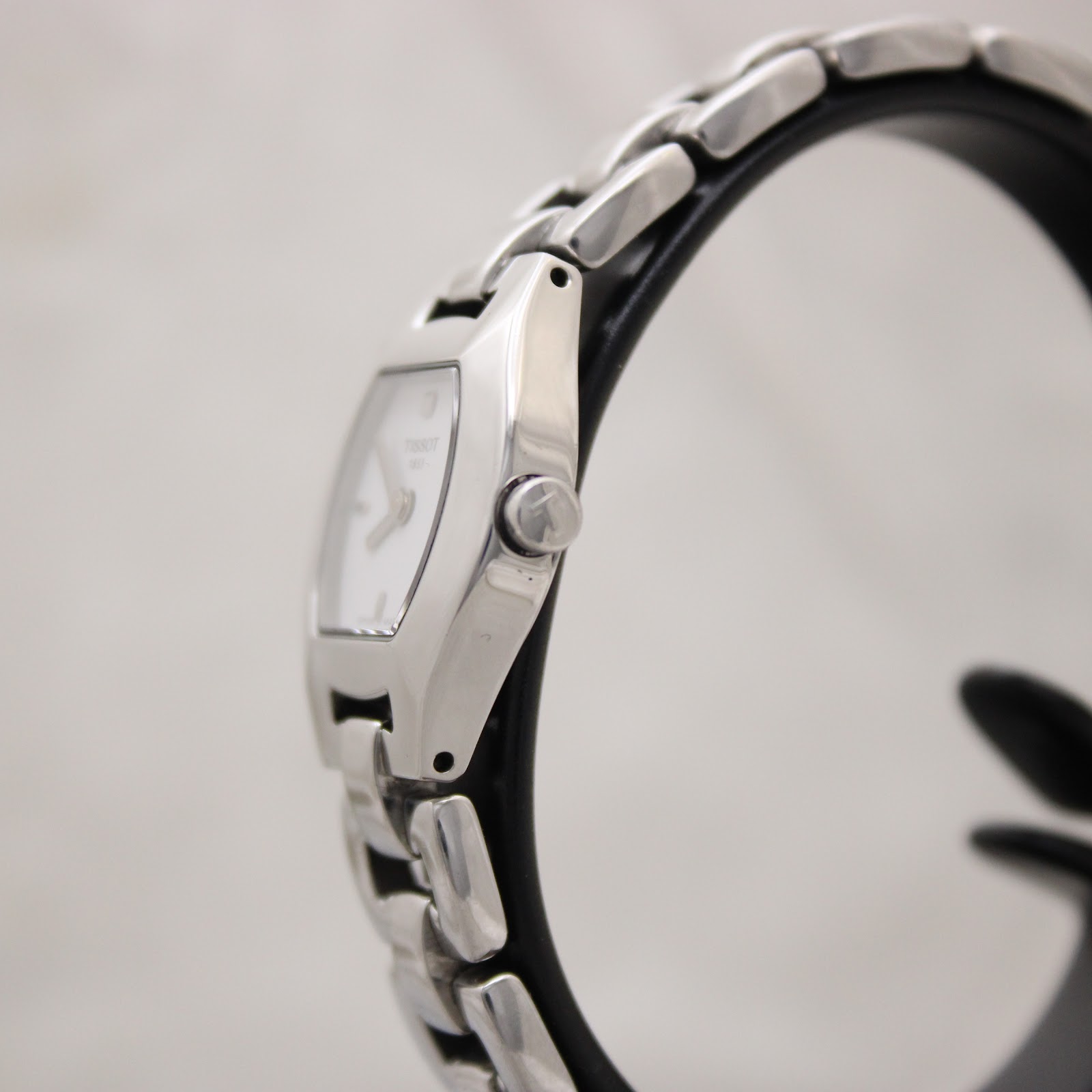 Side profile of the Tissot G333 watch on a stand, showing the curved tonneau-shaped case and original steel crown.