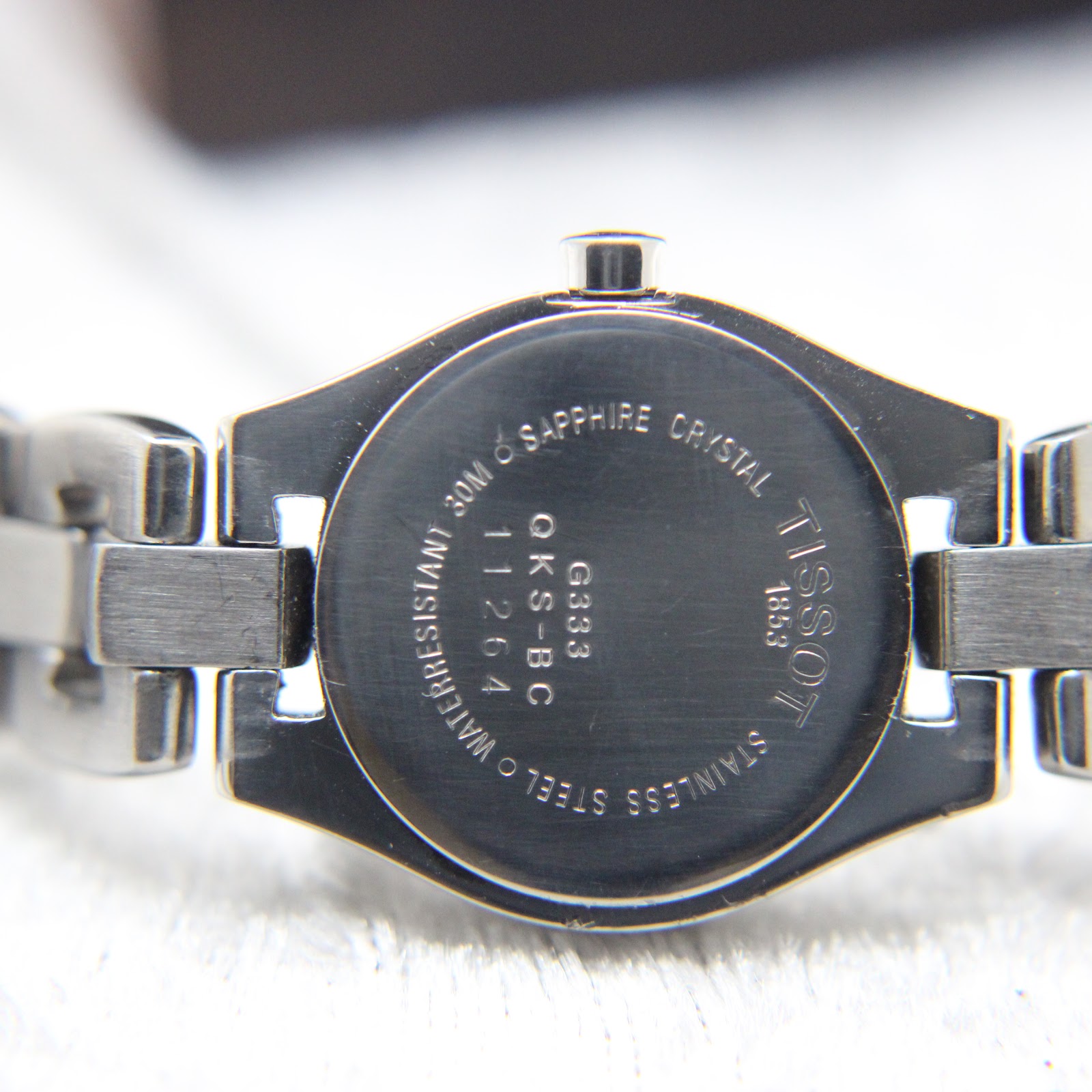 Close-up of the stainless steel case back of the Tissot G333, showing 'TISSOT 1853', 'G333 QKS-BC 11264', 'SAPPHIRE CRYSTAL', and 'WATER RESISTANT 30M'.