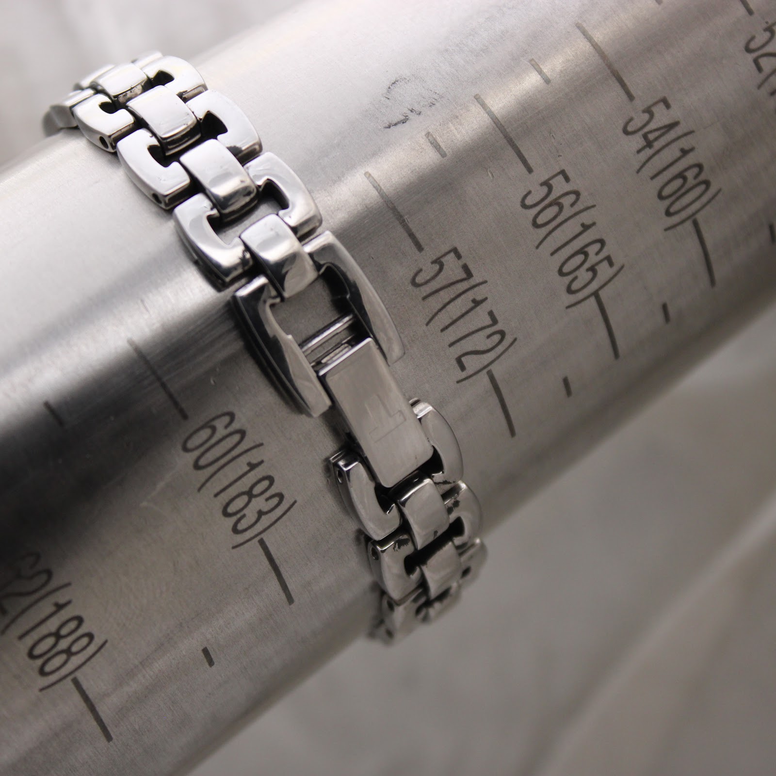 Close-up of the Tissot G333 stainless steel bracelet clasp on a wrist sizing gauge, showing a measurement around 172-175 mm (17.2-17.5 cm).