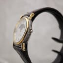 Side profile of the Montine watch, showing its two-tone case and gold-tone fluted crown.