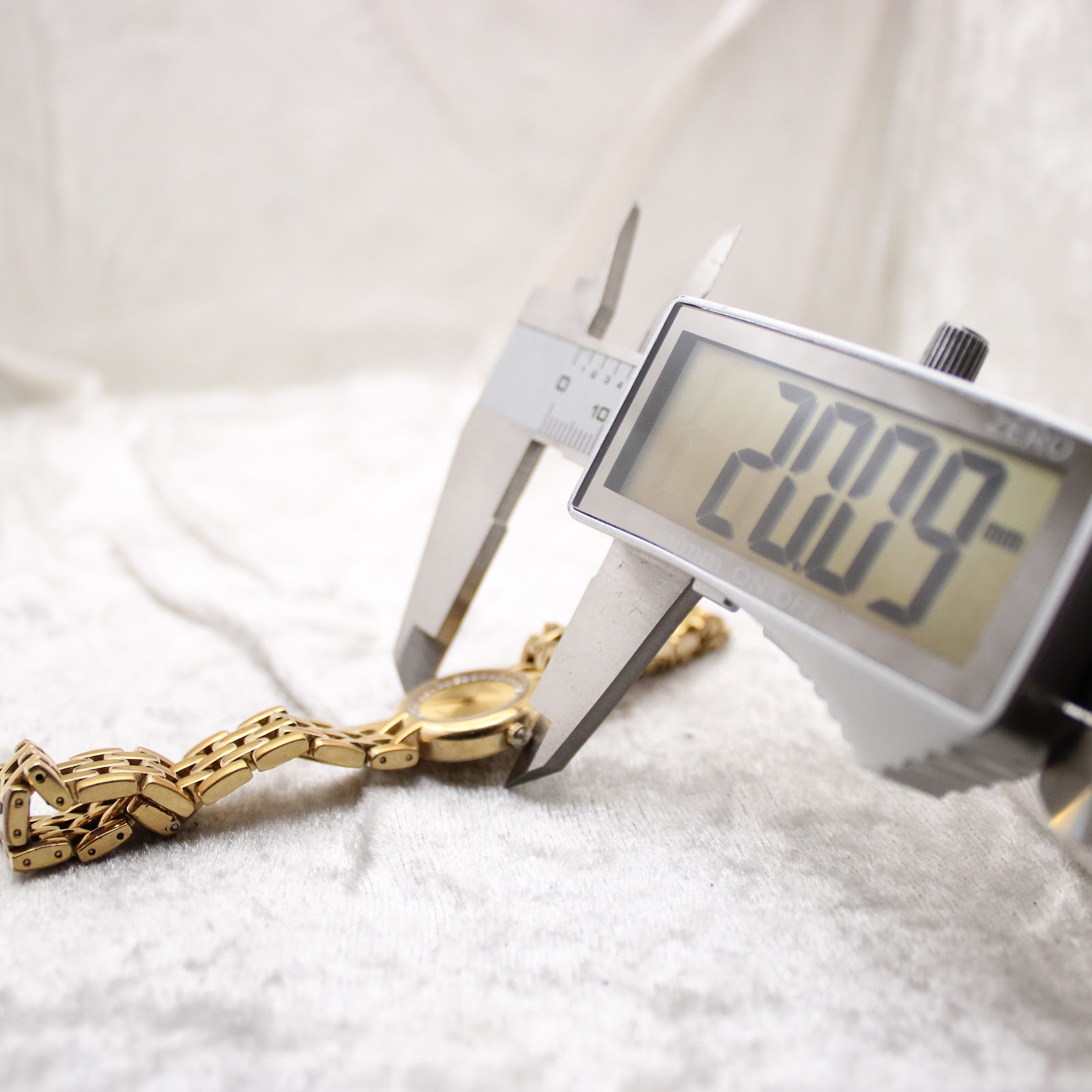 Close-up of a digital caliper measuring the Raymond Weil watch case, displaying a diameter of 32.32mm.